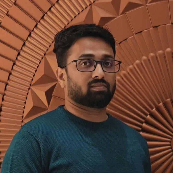 Pavan in a teal sweater in front of a terracotta wall