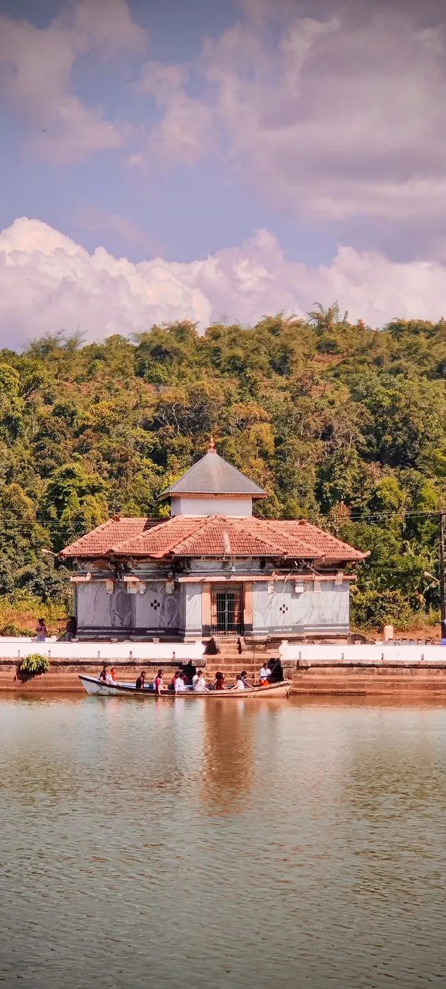 A small temple by a lake, reflected in the still water under a cloudy sky